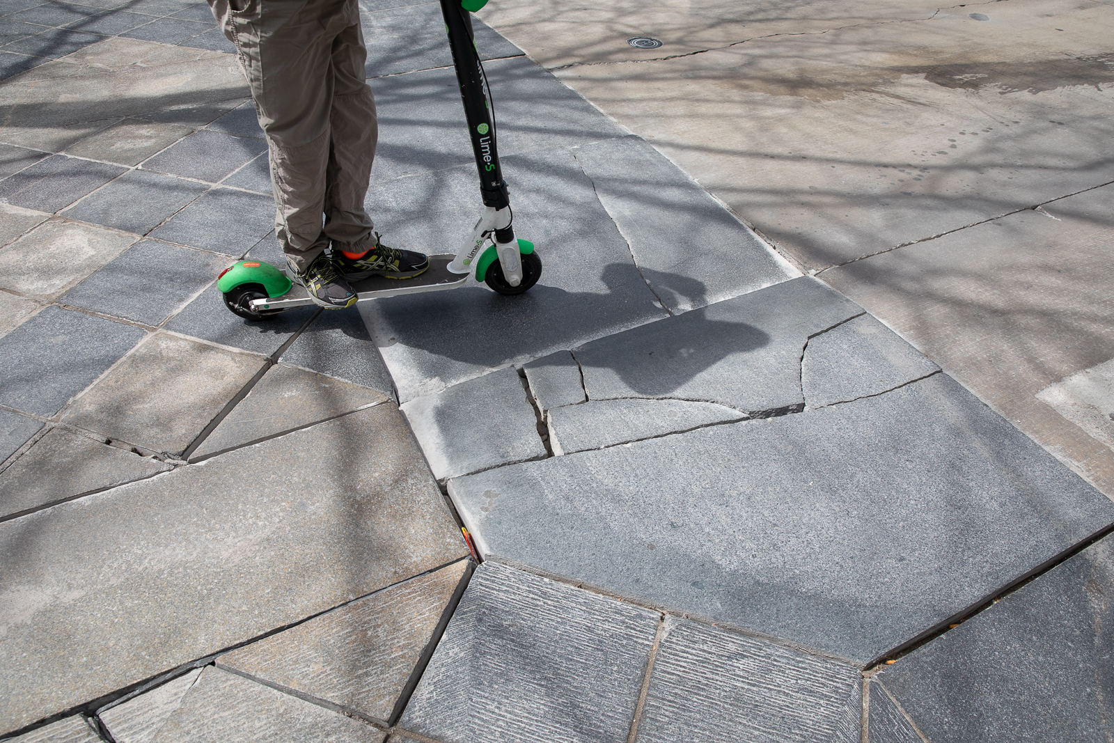 A scooter user passes around cracked and displaced tile on the 16th St. Mall. Photo: Andy Bosselman