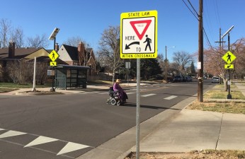 A person in a wheelchair crosses the street at 26th and Newton near a bus stop and an assisted living center for older adults in Sloan's Lake. Photo: David Sachs