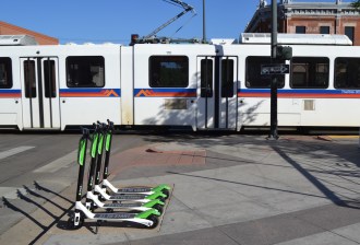 Photo of Lime scooter at 26th and Welton in Five Points and an RTD light rail train