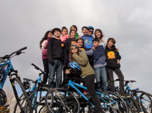 Students from the West Leadership Academy pose for a photo near the South Platte trail south of Mile High Stadium with Kat Andrus, who coordinates the bicycle program there for the nonprofit Mile High 360.