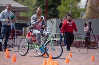 Ismael Mamdu, a student at DU, attempts to navigate an obstacle course on a tricycle while sending a text message. Photo: Andy Bosselman