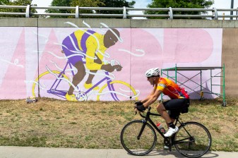 A cyclist passes the new mural of Major Taylor, the first African American to win a world cycling championship in 1899. Photo: Andy Bosselman