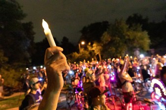 A crowd of people hold candles at a vigil