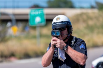 Sgt. Troy Zimmerman operates a lidar gun to determine the speed of vehicles on W. Colfax Ave. near Federal Blvd. this morning. Photo: Andy Bosselman