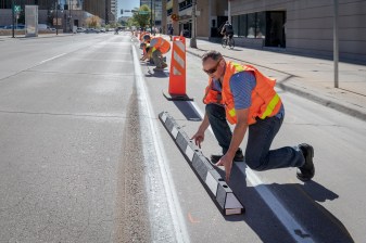 This morning workers made measurements to show installers where to put in rubber curbs along the 15th St. bikeway near Tremont Pl. Photo: Andy Bosselman