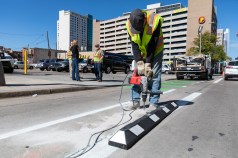 A Public Works employee drills a hole before installing a rubber curb along the 15th St. bikeway on Sept. 25. Photo: Andy Bosselman