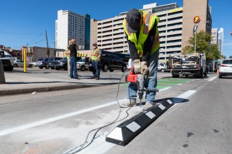 A Public Works employee drills a hole before installing a rubber curb along the 15th St. bikeway on Sept. 25. Photo: Andy Bosselman