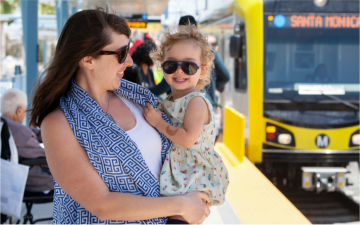 A woman carries a child on a rail platform. Photo: Metro L.A.