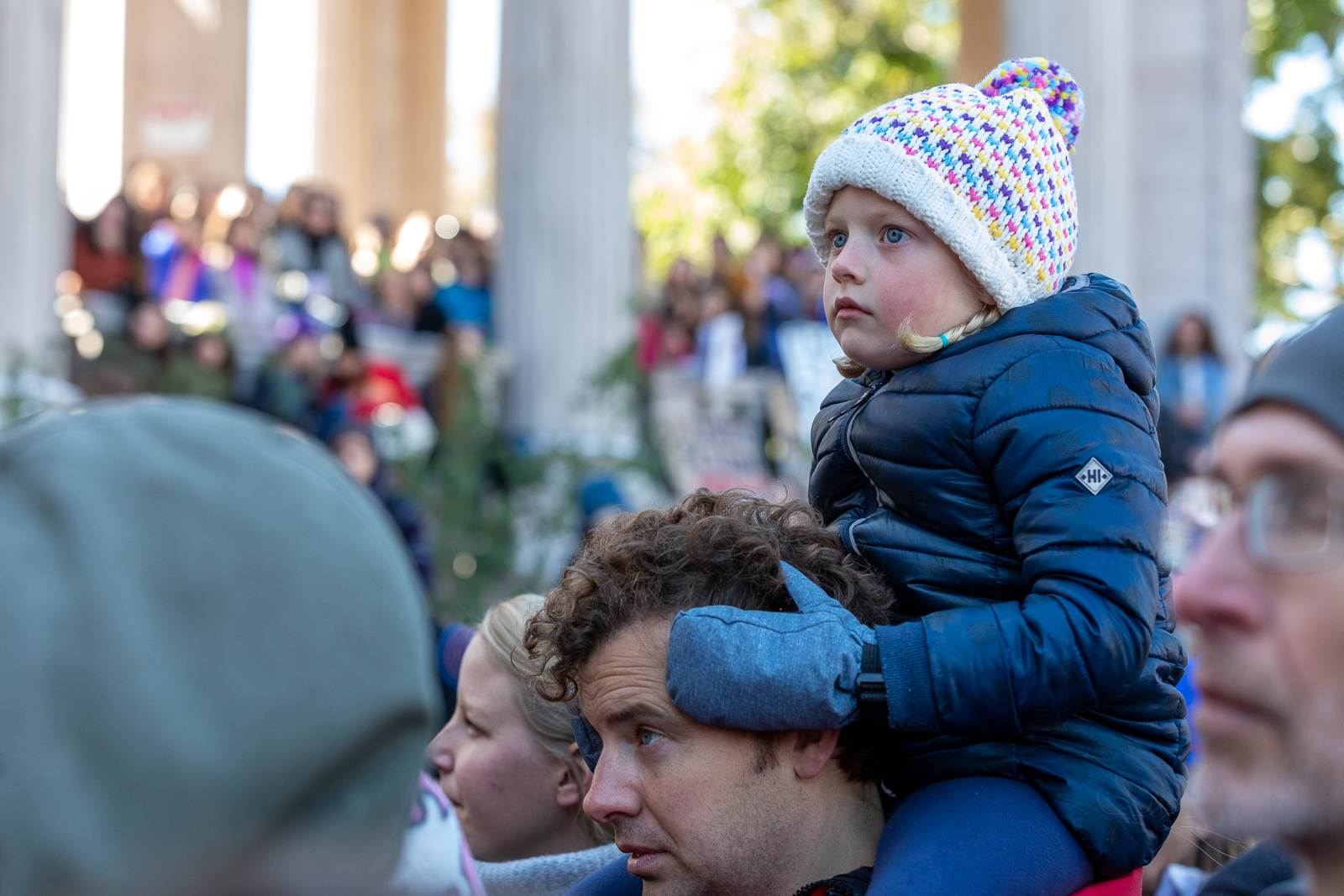 A girl watches speakers at the climate strike from the shoulders of a man. Photo: Andy Bosselman, Streetsblog Denver