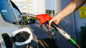Photo of a person's holding a gas pump nozzle to fill a car tank