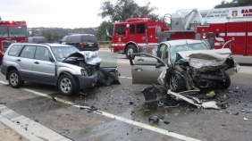 Photo post-crash photo of two smashed cars and fire truck in background