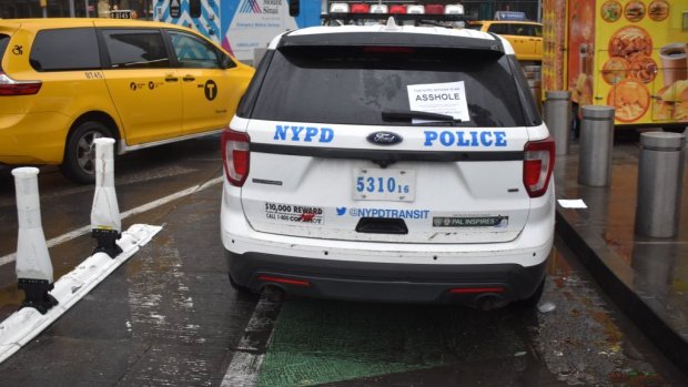 Photo NYPD car parked in bike lane with paper sign on back window