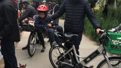 Photo a child strapped into a bike seat looks down at a dog