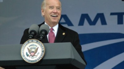 Joe Biden speaks at a vice presidential lectern in front of an Amtrak logo