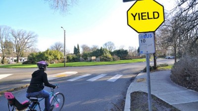 Photo person rides a bike in the street near a yield sign