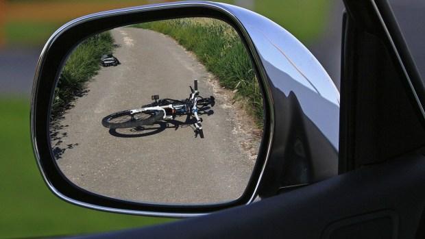 Bike on ground reflected in car's driver-side mirror