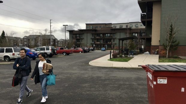 Two people walk in the parking lot of The Orchards at Orenco development, an affordable housing project next to a light-rail stop in Hillsboro, Ore.