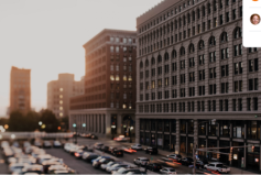 Parking lot full of cars near buildings of different heights
